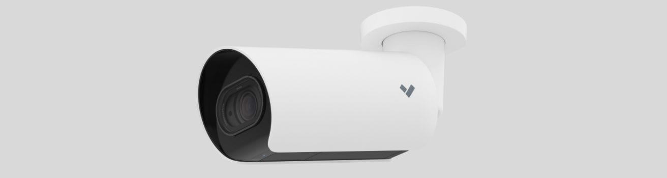 Commercial Security Camera Costs. A white cylindrical commercial security camera mounted on a wall, facing slightly downward, features a visible lens and a small logo on its side—ideal for businesses planning their 2026 security upgrades within a strict business budget.